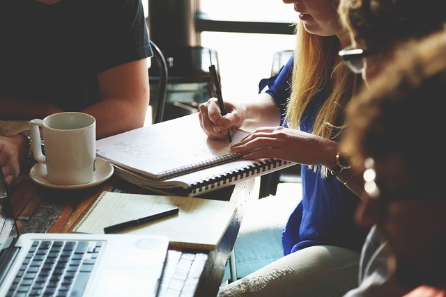 a group of people sitting at a table writing on a notebook